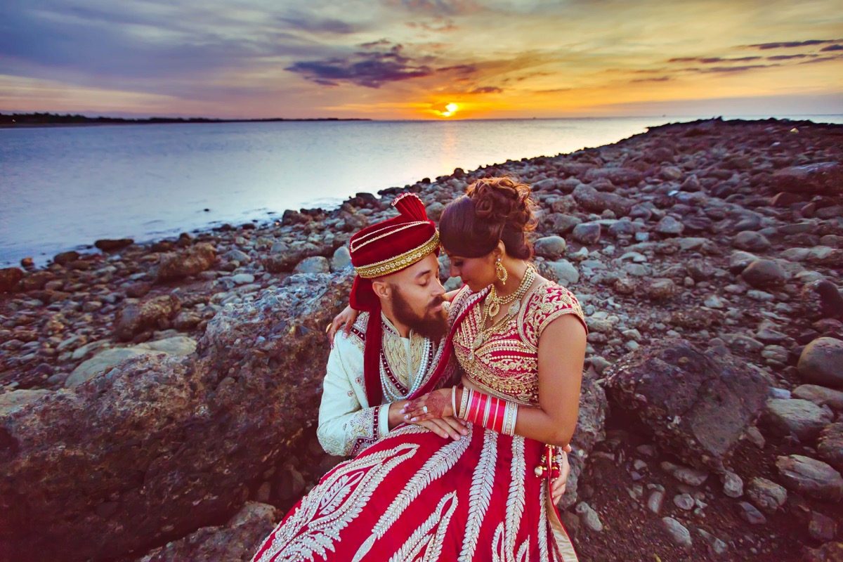 Couple in traditional dress on rocks at sunset